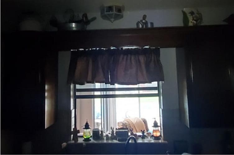 Before — dim kitchen window area in a Tulsa home with no overhead lighting