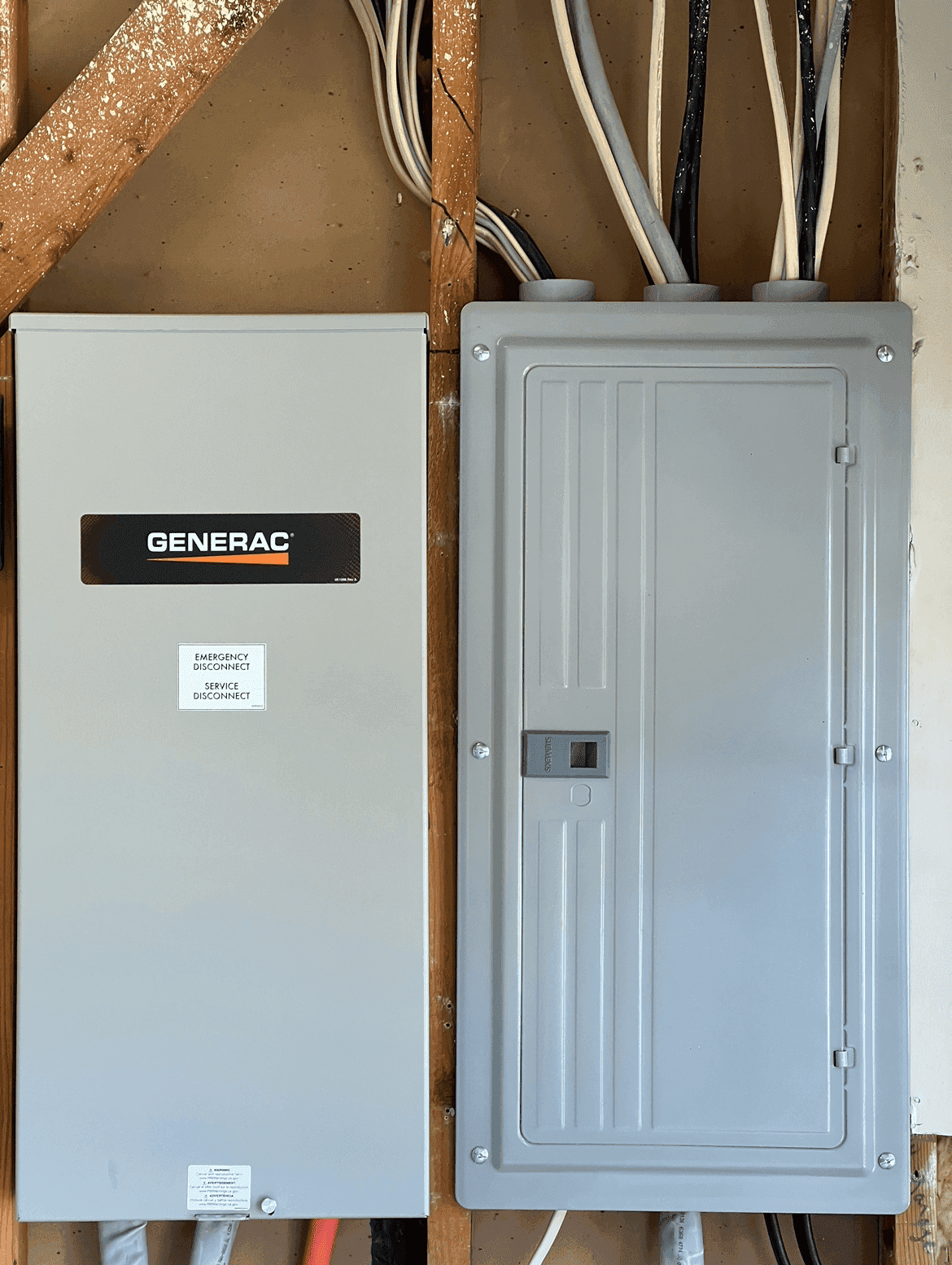 Generac whole-home standby generator transfer switch installed beside a residential breaker panel by M Electric in Tulsa