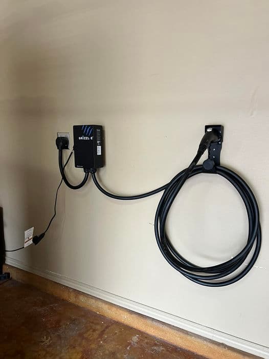 Grizzl-E Level 2 EV charger installed in a Tulsa-area garage by M Electric — clean mounting, proper dedicated circuit, cord routed for the actual parking position